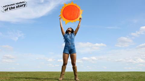 Woman holding model of sun aloft