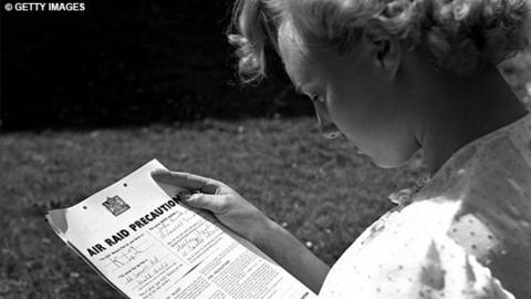 A women studies an Air Raid precaution leaflet.