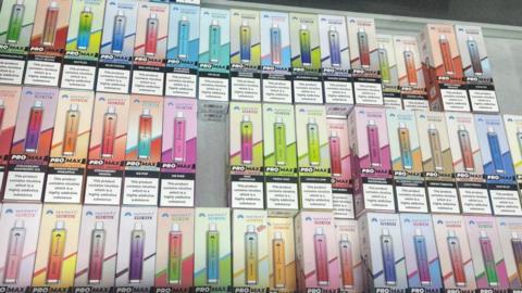 A stack of coloured vapes in boxes 