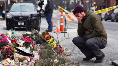 A person reacts at a makeshift memorial at the site where a man identified as Alex Pretti was fatally shot 