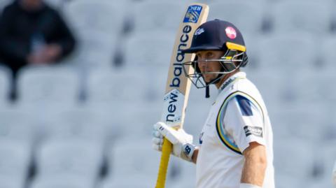 Joe Root raises his bat after scoring 50 against Warwickshire