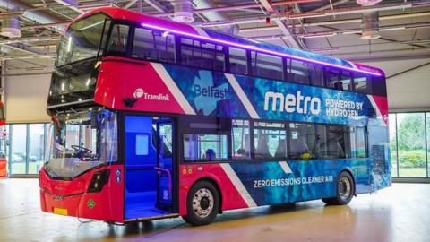 A pink and blue bus on display with a metro/translink signage on the side