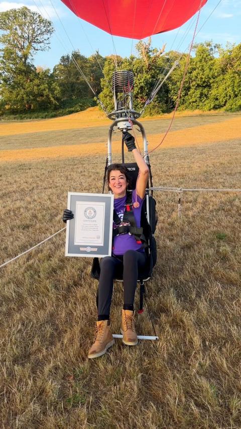Jo is on a small balloon hopper smiling at the camera and holding her award