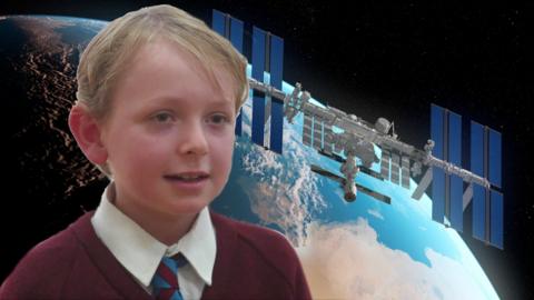 boy in front of image of the Earth and the ISS. 