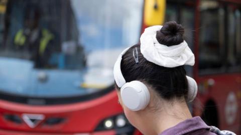 File image of a woman standing in front of a red double-decker bus in London