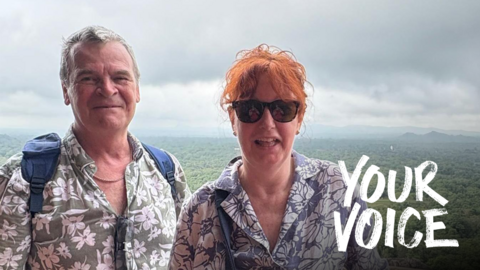 Ardon and Debbie Rainbird on holiday with a forest view behind them.