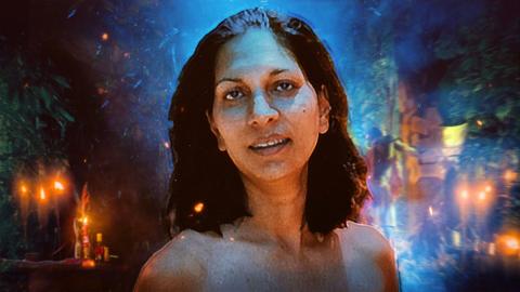 Juliette D'Souza - with dark curly hair, standing against a vivid, dreamlike background with glowing candles, blue and orange light, and abstract shapes creating a mystical atmosphere.