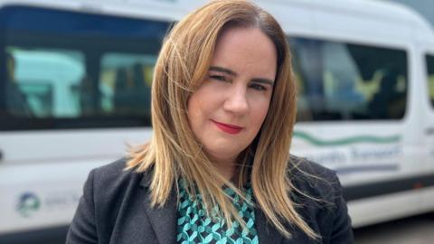 Noeleen Lynch stands in front of a community transport van 