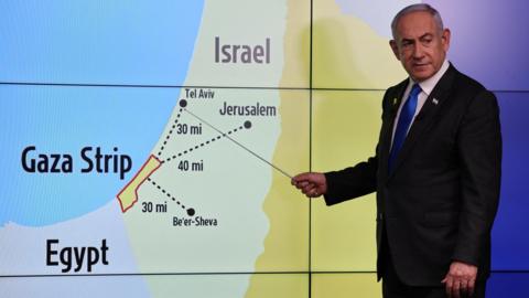 Israeli Prime Minister Benjamin Netanyahu stands before a map 