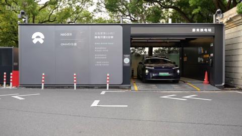 An electric car is parked inside a battery swap station