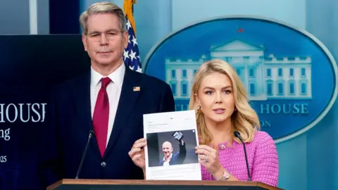 White House Press Secretary Karoline Leavitt (C) holds a photograph of Amazon founder Jeff Bezos with US Treasury Secretary Scott Bessent (L) during a press briefing at the White House, Washington, DC, USA, 29 April 2025.