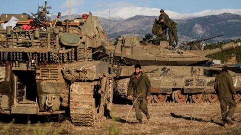 Israeli soldiers stand on a tank by Israel’s border with Lebanon in northern Israel, 26 November 2024