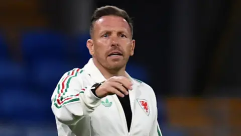Craig Bellamy with hand outstretched on touchline