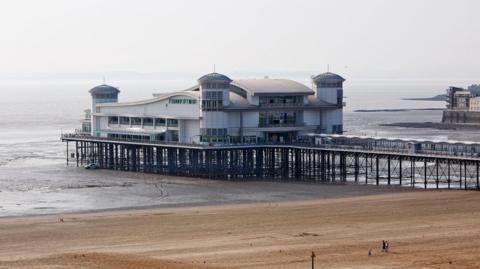 Weston-super-Mare's pier with sand in front and grey sky in the background.