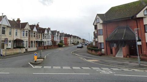 A Google Street View of a residential street of terraced houses branching off from a main road.