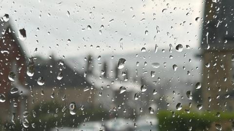 A window onto a street with raindrops in the foreground
