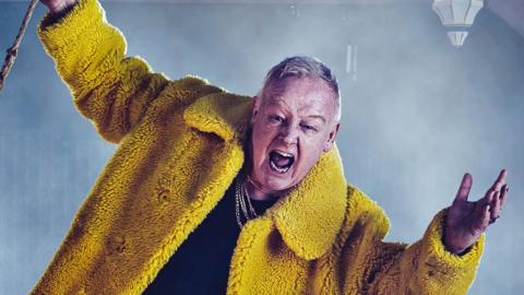 Promotional image for Twelfth Night at Shakespeare North Playhouse showing Les Dennis swinging on a chandelier