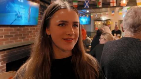 A woman standing in a pub