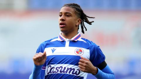 Michael Olise wearing a blue and white Reading FC shirt during a match. 