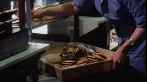 Workers in the Greggs seconds shop putting out pancakes