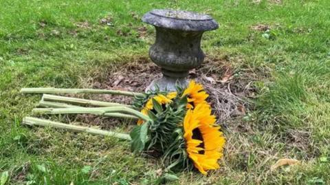 A bunch of sunflowers laid on the ground next to a grave marker