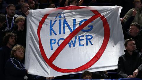 A sign is held by some Leicester City fans in protest of the club's ownership
