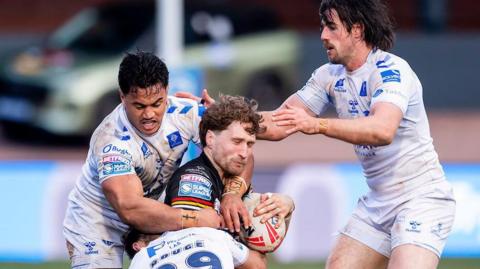 Bradford Bulls player Ethan Ryan is tackled by three Toulouse players.