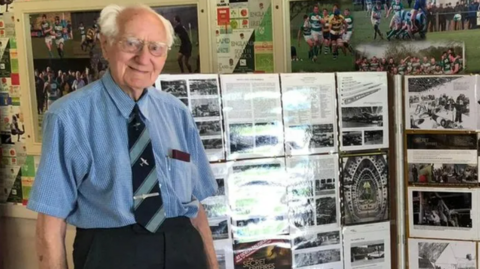 Man stood in front of stand with photos 