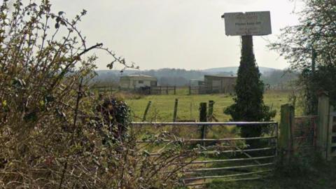 A field beyond a gate with hills in the background
