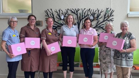 A row of woman – including nurses – holding pink Breast Friends boxes