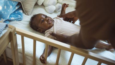 A baby is placed in a cot but its parent 