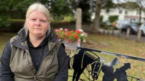 Helen Joyce sitting next to the war memorial in Cotgrave