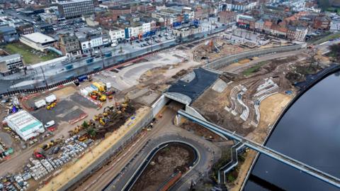 An aerial picture shows the riverside construction site with Stockton town centre in the background. The new road lay out can be seen as well as the granite amphitheatre and a partially constructed bridge across the river.