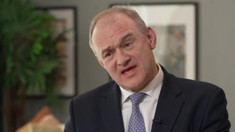 Ed Davey speaking to the BBC. He is wearing a dark suit and a blue patterned tie.