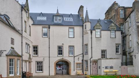 The Chambers Institution in Peebles viewed from an internal courtyard - a four-storey building of a greyish-brown colour with numerous windows and an arched doorway