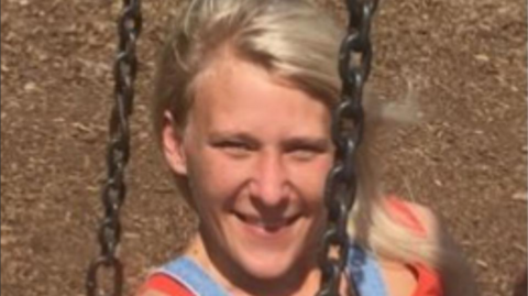 A smiling Charlotte Tetley relaxes on a swing, her blonde hair blowing in the wind