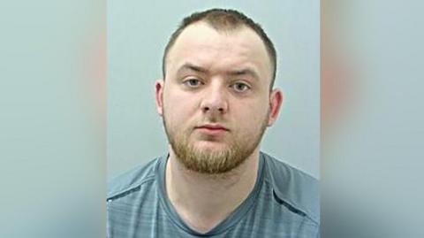 Police custody image of Jordan O'Brien with short brown hair and beard in a grey t-shirt