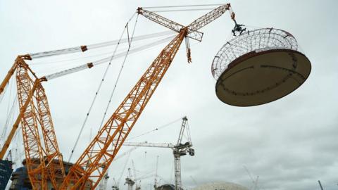 A large land crane lifts a 245-tonne domed roof onto the second reactor building at the Hinkley Point C nuclear power station, near Bridgwater. The photo has been taken on a cloudy day