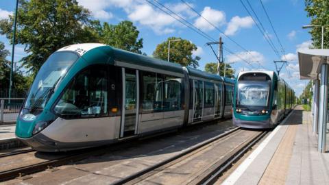 Two Nottingham trams on the track near a platform.