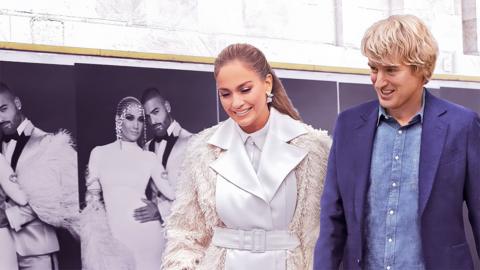 Two people walk past large fashion photographs.