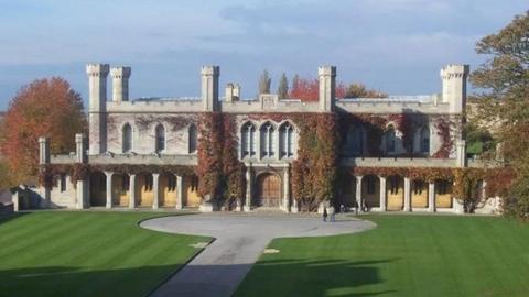 Historic ivy-covered grey court building in the grounds of Lincoln Castle, with a path and lawned area in the foreground