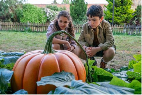 Two children look at giant pumpkin from the new Sky film Grow