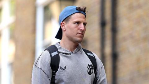 Brydon Carse, wearing a grey hoodie and backwards blue cap