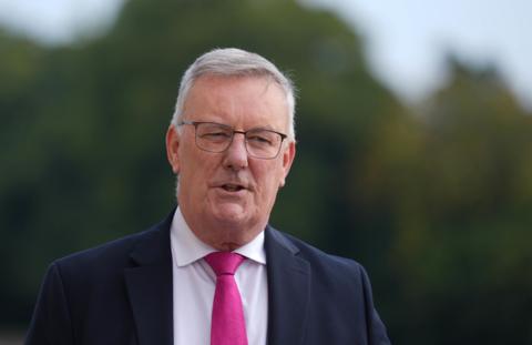 Mike Nesbitt wearing a navy suit and pink tie