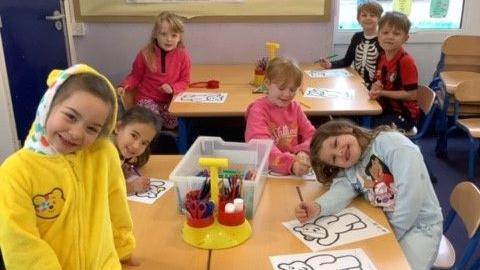 Children from Bransgore C of E Primary School at a table colouring images of Pudsey