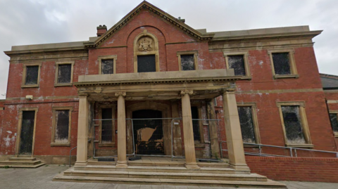 A dilapidated frontage of an abandoned swimming baths.