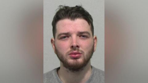 Mugshot of Stephen Scott. He has short dark hair swept back up on his head and a gingery straggly beard. His face is red and his thick lips appear to be in a slight pout.