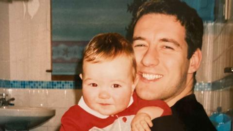 In a family photo Alistair Wilson is smiling as he holds his young son Andrew.