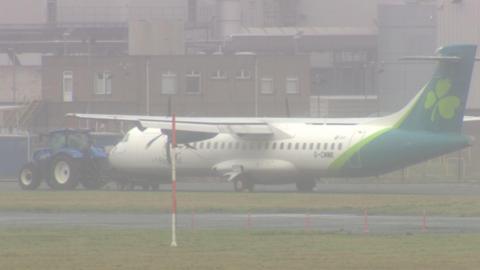 An Aer Lingus plane with a blue tractor parked in front of it. 