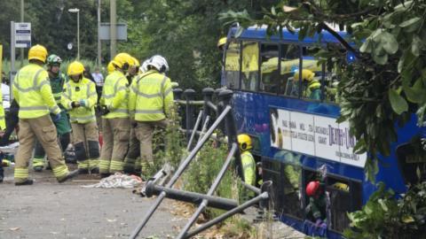 Emergency services near a bus with broken railings in the foreground